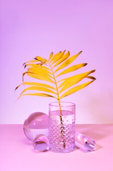 Feuille tropicale jaune dans un verre d'eau nature morte