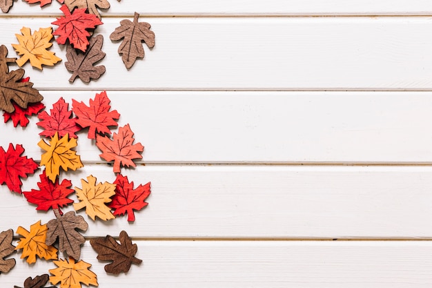 Photo gratuite feuilles d'érable artificiel sur fond en bois blanc