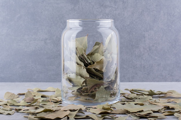 Feuilles de laurier sèches vertes dans une tasse sur une surface en béton