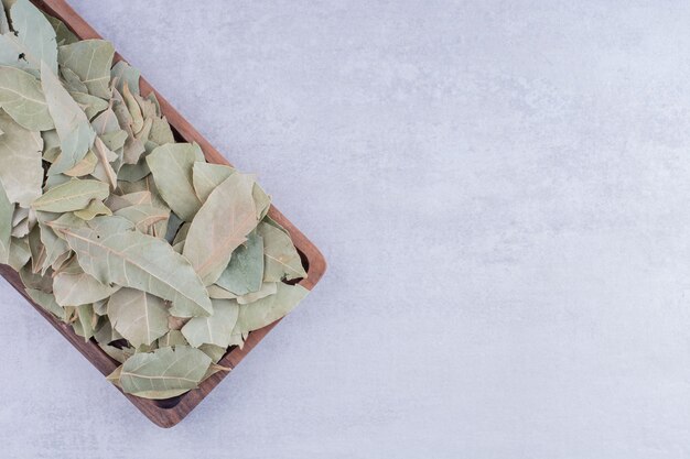 Feuilles de laurier sèches vertes sur un plateau en bois