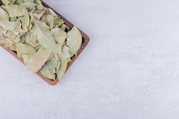 Feuilles de laurier vertes sèches sur un plateau sur fond de béton. photo de haute qualité