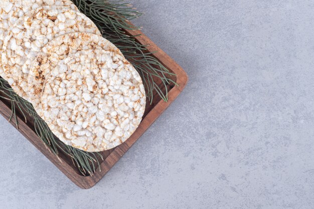 Feuilles de pin ornant un plateau de biscuits sur table en marbre.