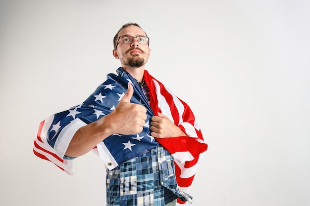 Photo gratuite fier jeune homme tenant le drapeau des états-unis d'amérique isolé sur blanc studio.