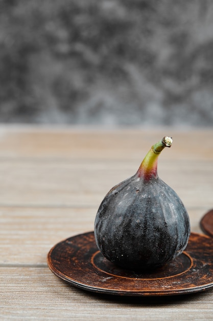 Une figue sur une petite assiette et sur une table en bois.