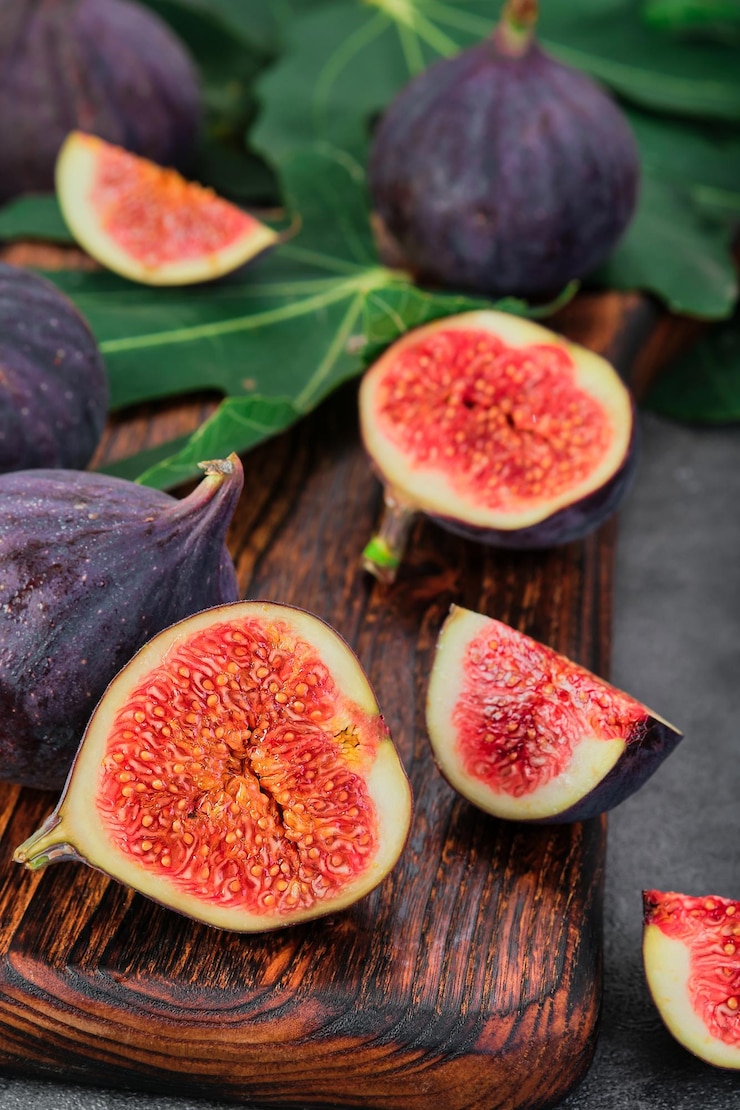 Photo gratuit figues coupées en tranches sur une planche à découper en bois closeup mise au point sélective cadre vertical fruits mûrs de saison idée de régime méditerranéen pour le fond