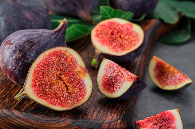 Figues coupées en tranches sur une planche à découper en bois mise au point sélective gros plan Cadre horizontal fruits de figues mûres saisonnières régime méditerranéen idée pour la publicité