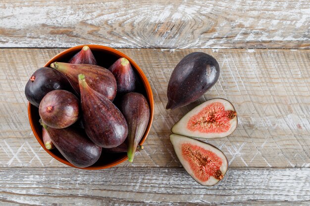 Figues et moitiés de mission dans un bol et autour de la vue de dessus sur une table en bois