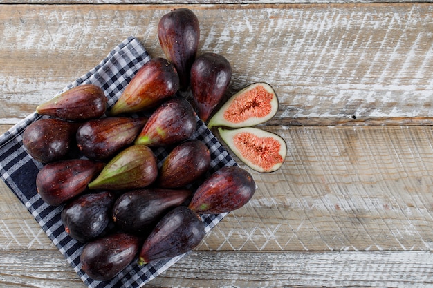 Les figues et les moitiés de mission vue de dessus sur un tissu de pique-nique et un espace de table en bois pour le texte