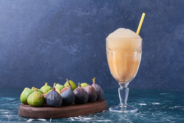 Figues avec une tasse de boisson sur bleu.