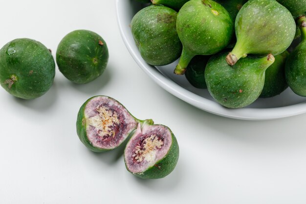 Figues et tranches dans une assiette sur un mur blanc. vue grand angle.