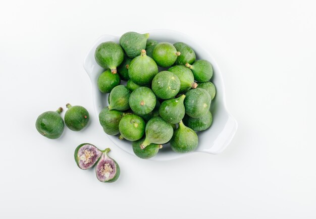 Figues et tranches dans une assiette plate posée sur un mur blanc