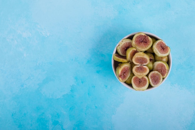 Figues vertes aux graines rouges dans un bol en céramique blanche, vue du dessus