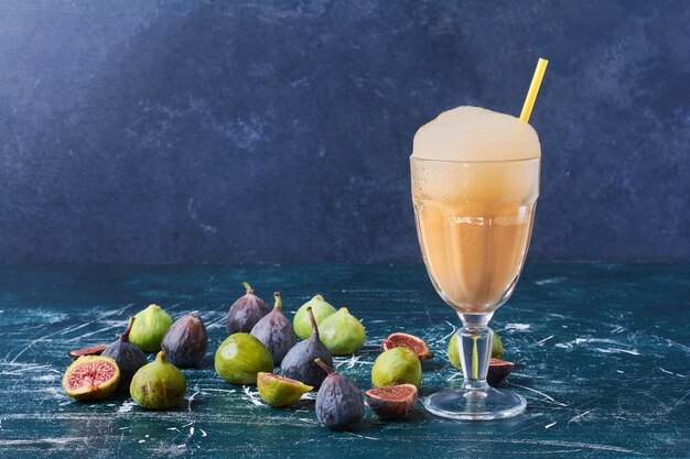 Figues vertes avec une tasse de boisson sur bleu.