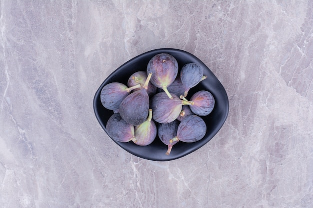 Figues violettes dans un bol noir en céramique, vue du dessus.