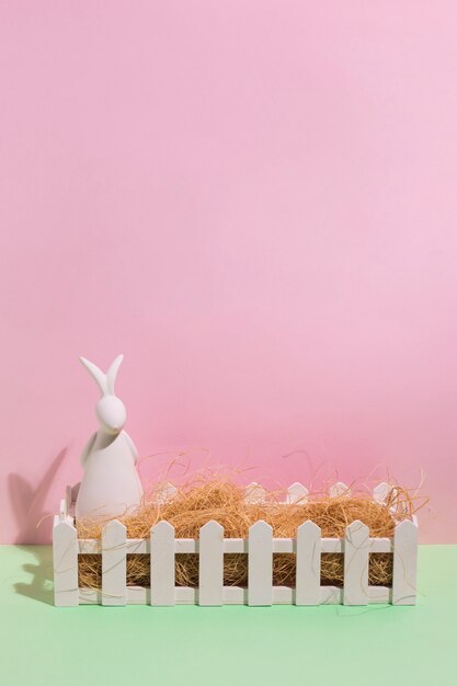 Figurine de lapin blanc avec du foin dans une boîte sur la table