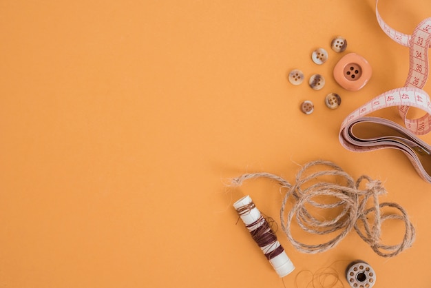 Fil de jute; bouton; ruban à mesurer et bobine sur fond coloré