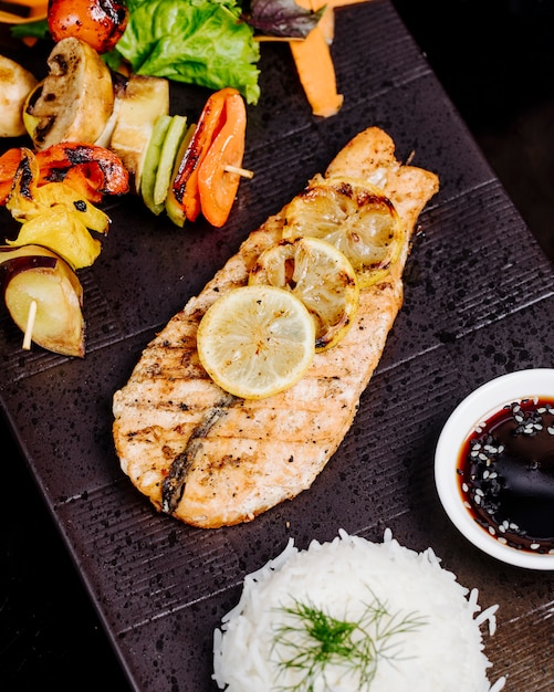 Photo gratuite filet de poisson grillé au citron, bâtonnet de légume, riz et sauce.