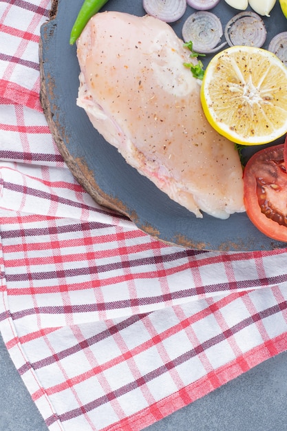 Photo gratuite filet de poulet non cuit sur planche de bois avec des légumes.