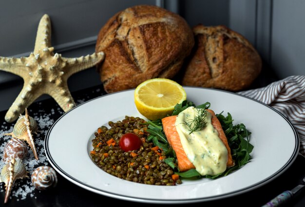 Filet de saumon frit garni de sauce, servi avec lentille et carotte rôties