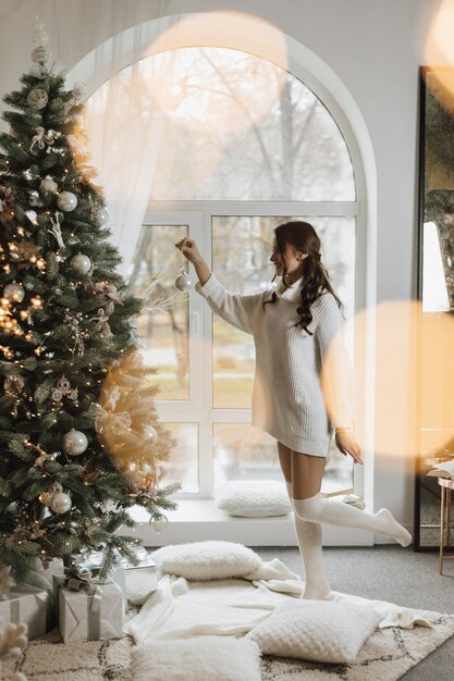 Fille accroche un jouet sur un arbre de Noël