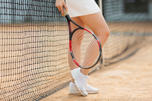 Fille active debout à côté du filet de tennis