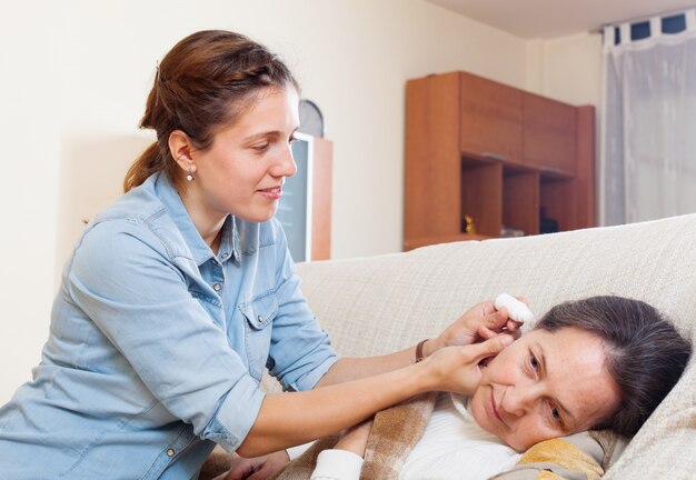 Fille adulte dégoulinant des gouttes d&#39;oreille à la mère mûre