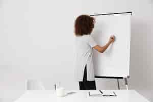 Photo gratuite fille africaine écrit debout près du tableau blanc marqueur. copiez l'espace.