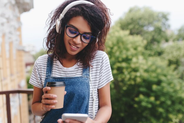 Fille africaine à la mode avec un message texte de longs cils et tenant une tasse de café sur la nature