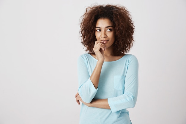 Fille africaine rêveuse pensant souriant. mur blanc. Copiez l'espace.