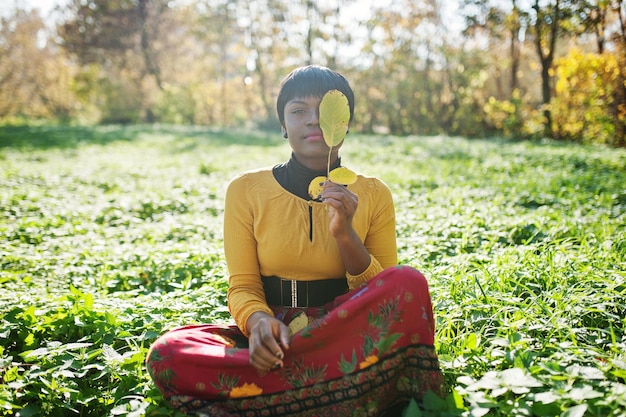 Fille afro-américaine en robe jaune et rouge au parc d'automne automne