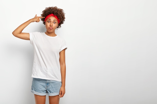 Photo gratuite fille afro drôle folle tire dans le temple avec le doigt, les gestes à l'intérieur