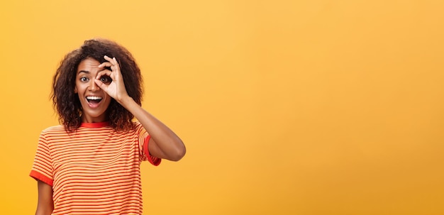 Une fille d'âge adulte à la peau sombre créative et ludique avec une coiffure bouclée dans un t-shirt rayé montrant