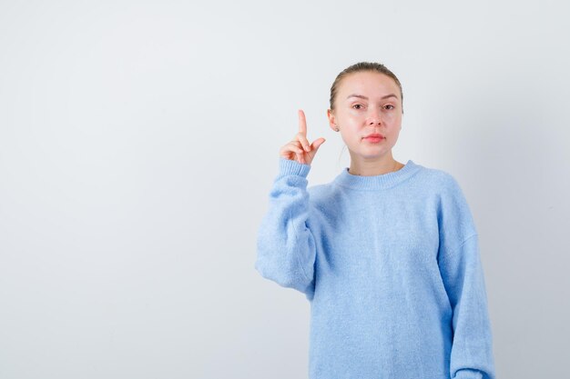 Une fille agréable montre ses doigts sur fond blanc