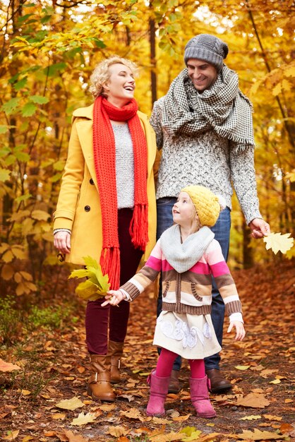 Fille aidant les parents à ramasser des feuilles