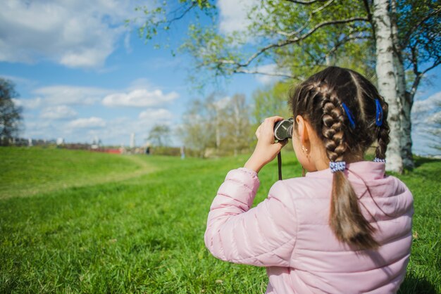 Fille analysant le parc avec ses jumelles