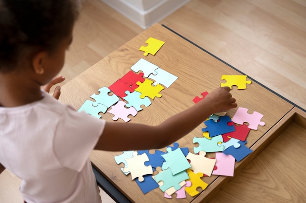 Fille à angle élevé faisant un puzzle à l'intérieur