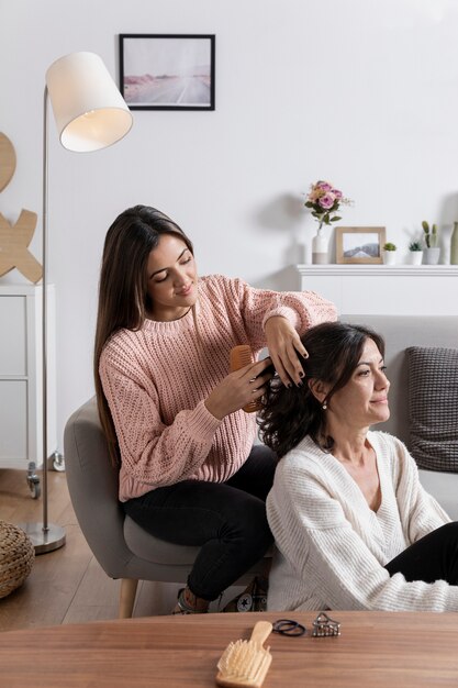 Fille d'angle élevé tressant les cheveux de maman