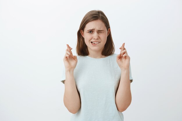 fille anxieuse et nerveuse croisant les doigts pour la bonne chance jetant un œil au tableau des résultats en attendant les notes être anxieuse et inquiète prier pour que le souhait se réalise