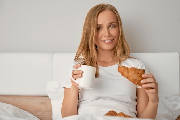 Fille appréciant le petit déjeuner au lit