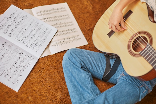 Fille apprenant à jouer de la guitare à la maison