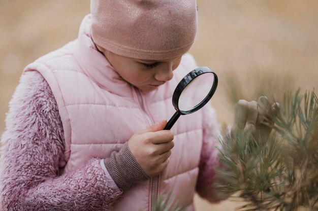 Fille apprenant la science dans la nature avec une loupe