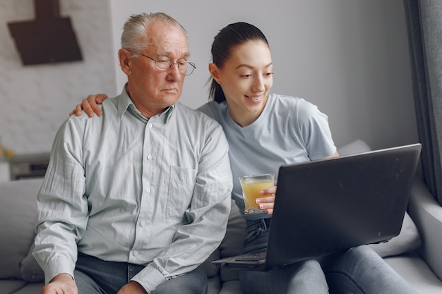 Fille apprenant à son grand-père comment utiliser un ordinateur portable