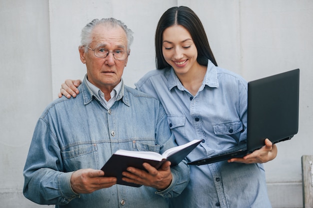 Fille apprenant à son grand-père comment utiliser un ordinateur portable