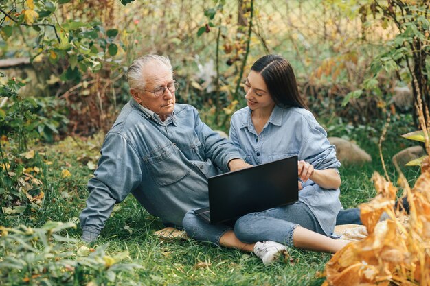 Fille apprenant à son grand-père comment utiliser un ordinateur portable