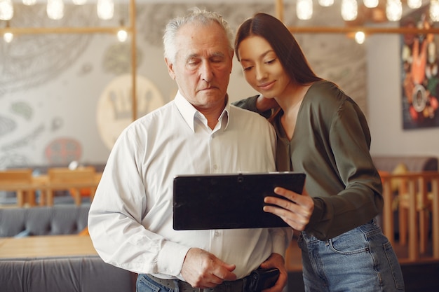 Fille apprenant à son grand-père comment utiliser une tablette