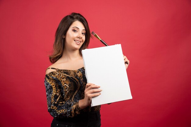 Fille d'artiste tenant son œuvre d'art sur toile et la démontrant au public.