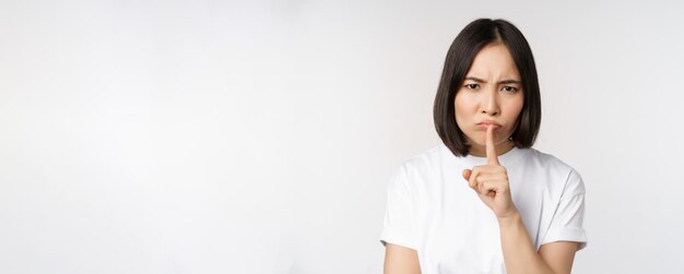 Fille asiatique en colère chut garder le silence tabou silence geste appuyez le doigt sur les lèvres et fronçant les sourcils