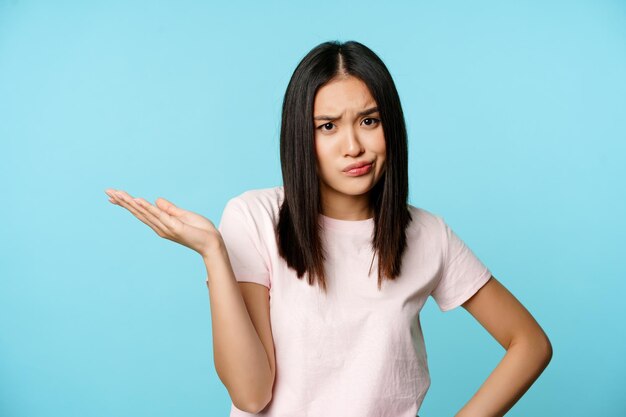 Une fille asiatique frustrée haussant les épaules, l'air dérangée et agacée, ne peut pas comprendre qch debout en t-shirt...