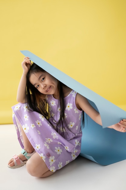 Photo gratuite fille asiatique jouant avec du papier bleu