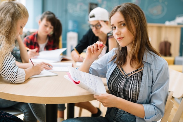 Fille assise et apprenant avec les camarades